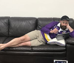 A man reading a book on the couch