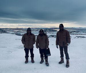 Three electricians standing on the ice near station