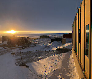 Looking over station buildings, thee sunrise peeking through the gap between the snow and the cloud