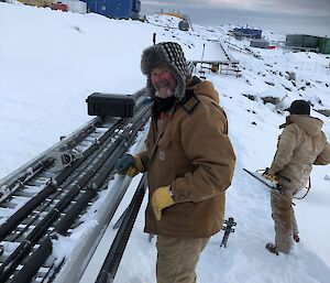 Two plumbers replacing a section of fuel line over snow