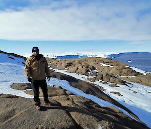 An expeditioner stading on snow covered rocks