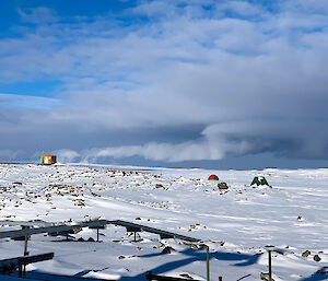 Convective rising of cumulus clouds, behind the hut on the hill, into a layer of stratocumulus clouds