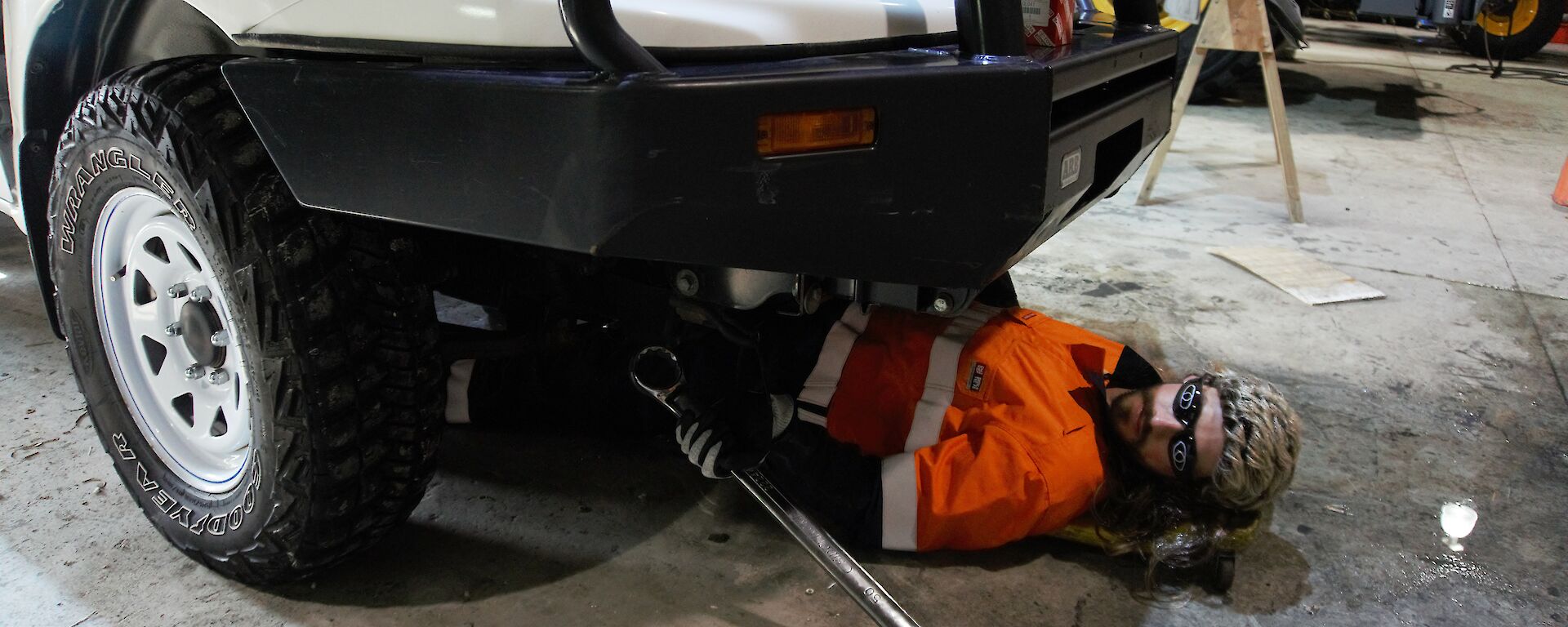 Field training officer in the vehicle workshop, lying under a vehicle