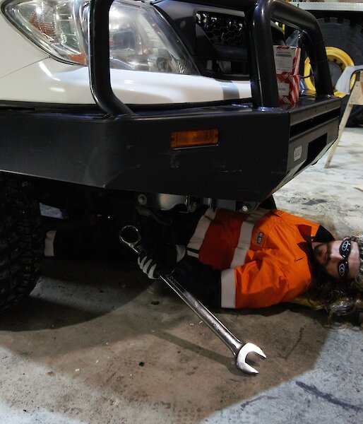 Field training officer in the vehicle workshop, lying under a vehicle