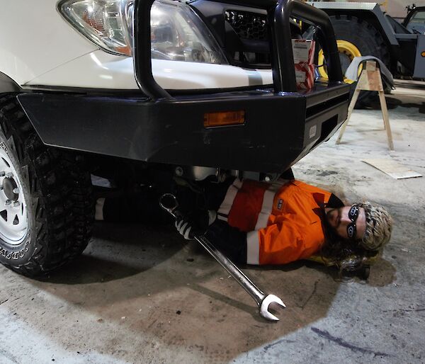 Field training officer in the vehicle workshop, lying under a vehicle