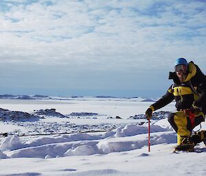 An expeditioner kneeling on the ice