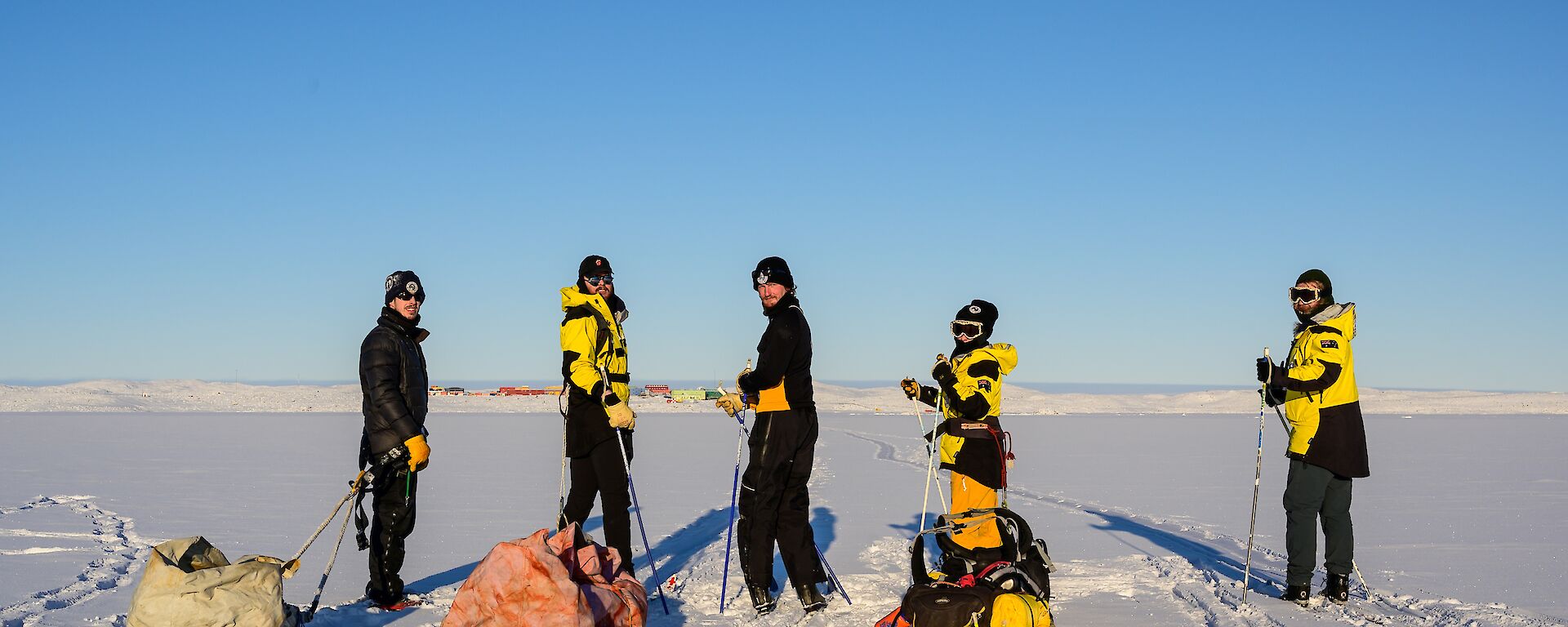 Five expeditioners of the ski group look back intrepidly over their sleds toward the camera