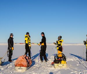 Five expeditioners of the ski group look back intrepidly over their sleds toward the camera