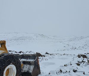 The CAT loader heading into the snowy rocky hills