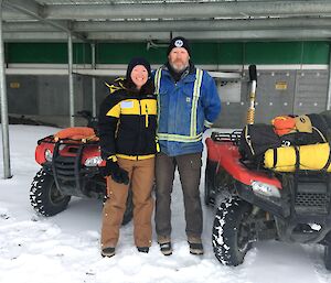 Two expeditioners pose in front of their quad bikes