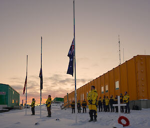 Expeditioners gather at dawn at the flags which are at half mast.