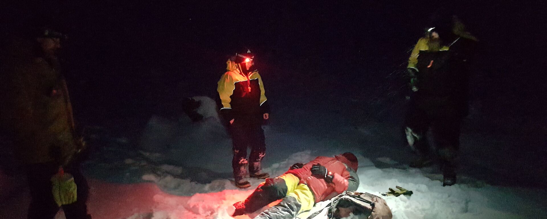 Jason the “casualty” lies on the snow covered ground in the dark surrounded by rescuers