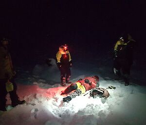 Jason the “casualty” lies on the snow covered ground in the dark surrounded by rescuers