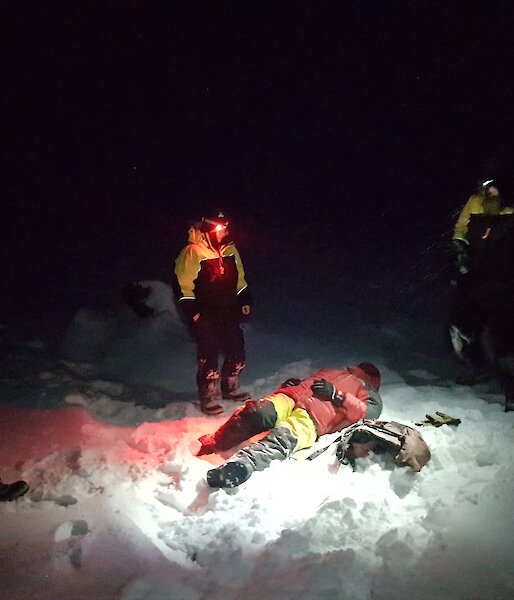 Jason the “casualty” lies on the snow covered ground in the dark surrounded by rescuers