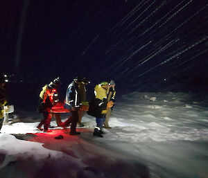 A team carries the orange stretcher to safety through the snowy, pitch black morning