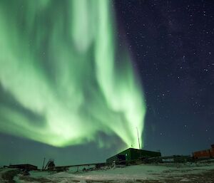 A green Aurora Australis over station buildings