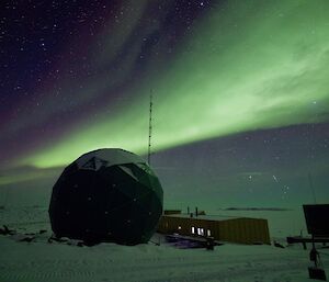an aurora australis beam shoots over the satellite dome