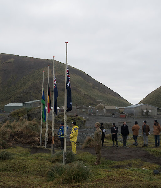 Group of expeditioners gathered around flag poles