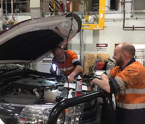 Two expeditioners working under the bonnet of a vehicle in the workshop
