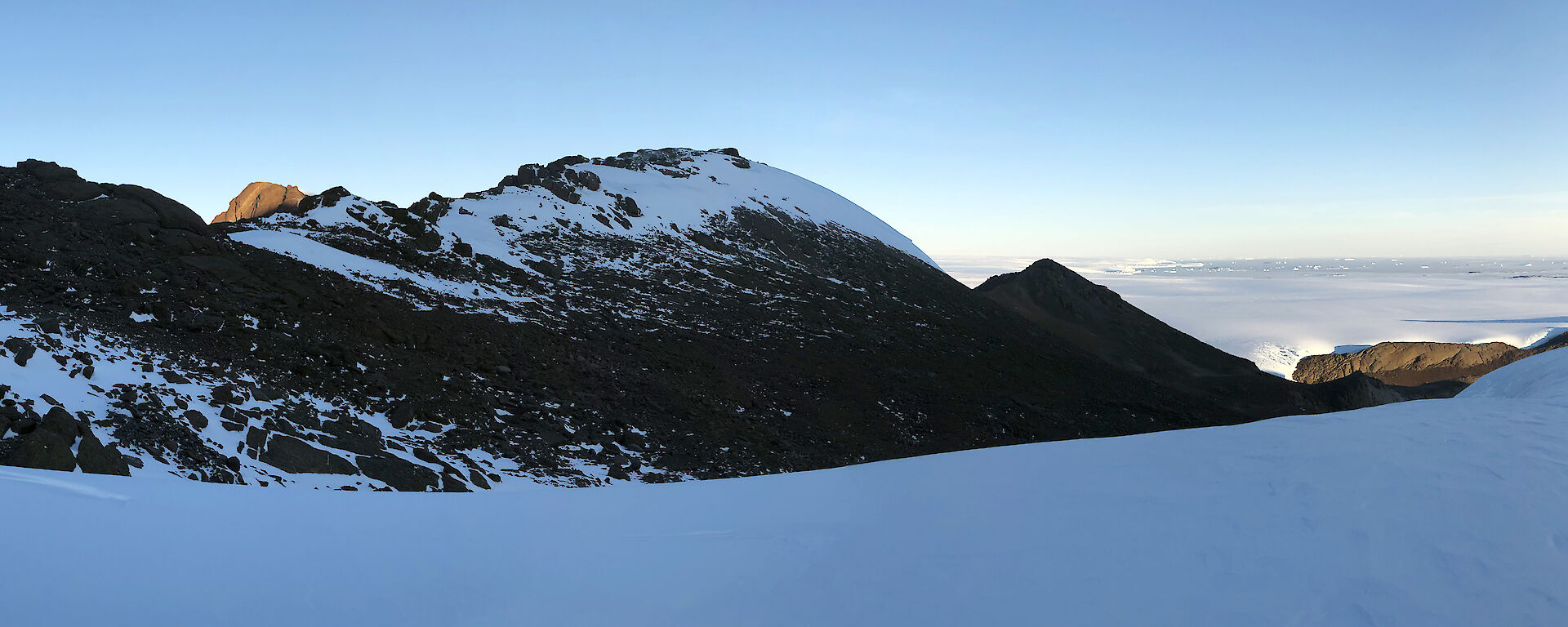 Panorama of snow covered mountains and a field hut