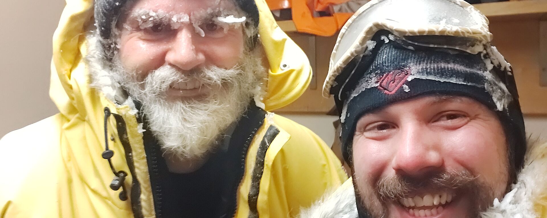 Two expeditioners with ice on their clothes and gear