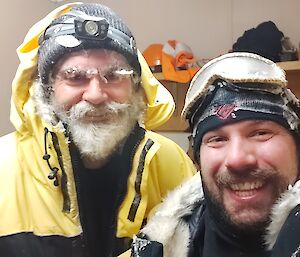Two expeditioners with ice on their clothes and gear