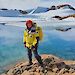 Dana Bergstrom standing beside a lake with ice covered hills behind.