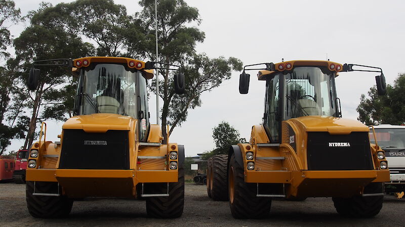 Two yellow tip trucks side by side.