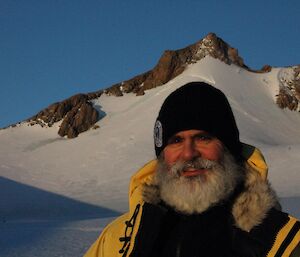 An expeditioner standing at the base of a snow covered mountain