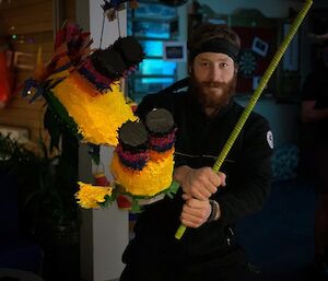 Man holding a long stick getting ready to hit a pinata