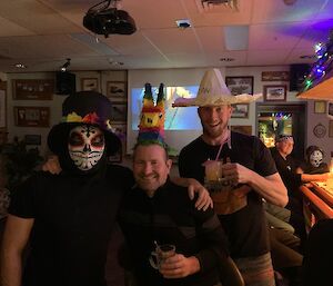 group photo of three expeditioners wearing mexican hats at the bar