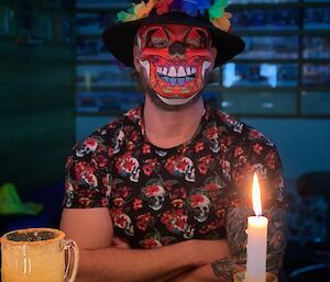 A masked man sitting at a table by candlelight