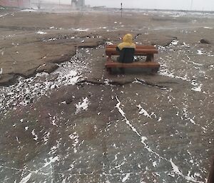 An expeditioner sitting at a picnic table alone