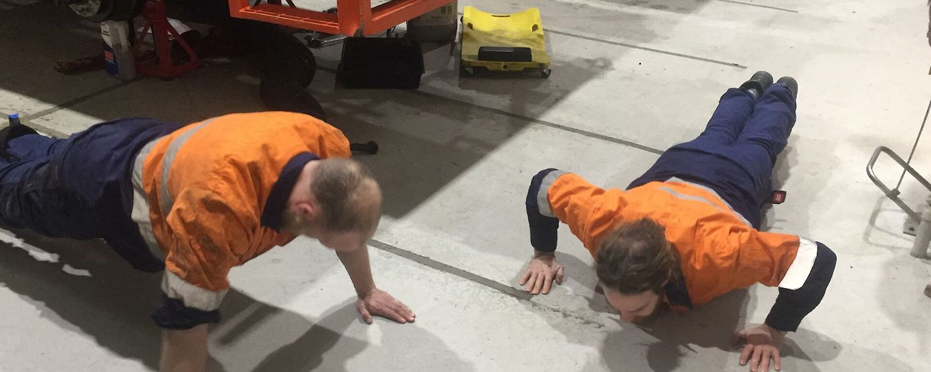 Two expeditioners doing push ups in the workshop