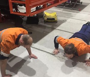 Two expeditioners doing push ups in the workshop