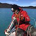 Scientist sampling water from an Antarctic lake in an inflatable rubber boat.