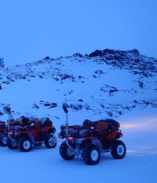 four quad bikes in front of a landscape of snow and rocks