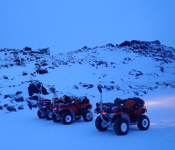 four quad bikes in front of a landscape of snow and rocks