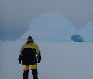 Jay standing on the frozen sea with large icebergs littering the background