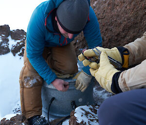 An expeditioner checking a communications repeater on snow covered rocks