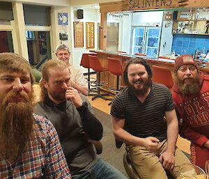 Four men sporting their beards with one clean-shaven man sitting behind them