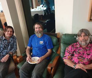 Three men sporting varying degrees of facial hair while sitting in comfy bar chairs