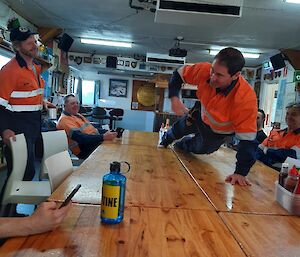 An expeditioner doing a one handed push up on a table