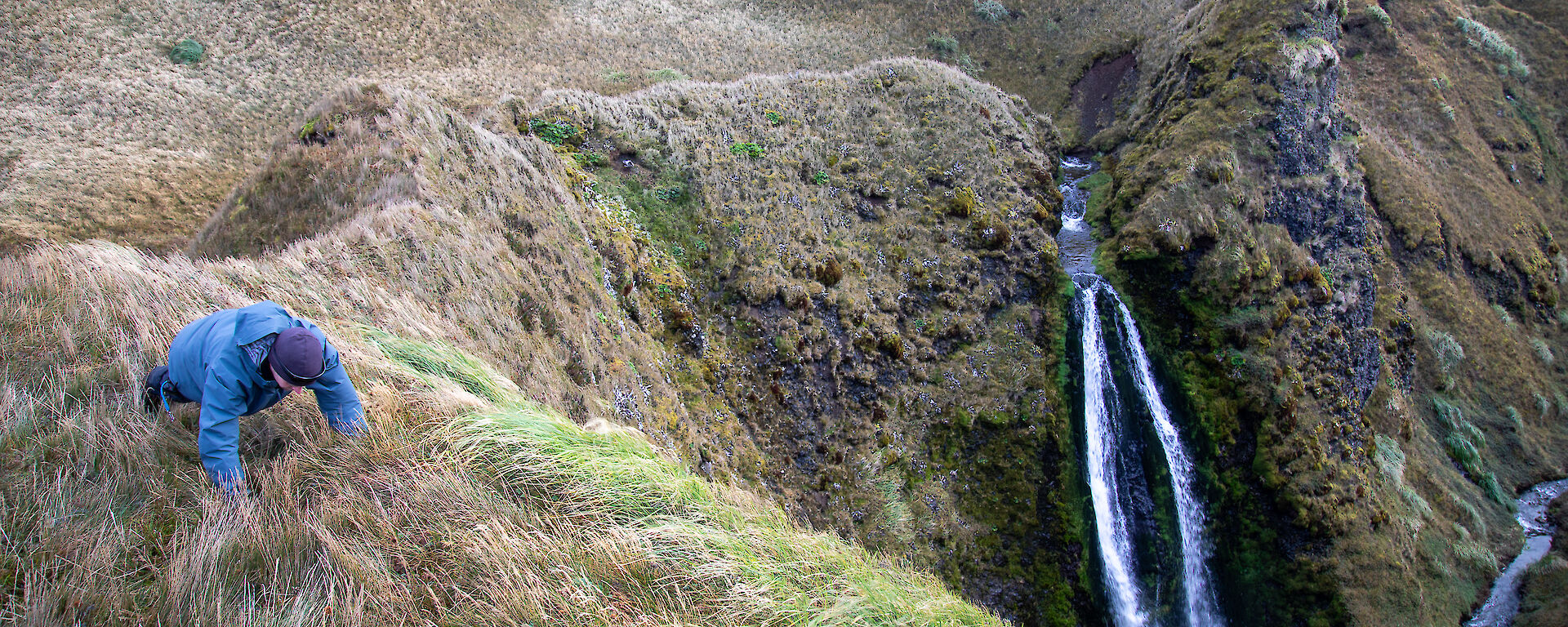 An expeditioner doing push ups on a ridge near a waterfall