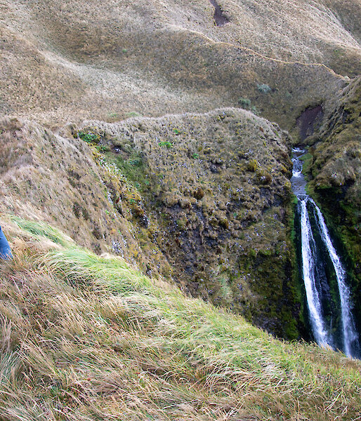 An expeditioner doing push ups on a ridge near a waterfall
