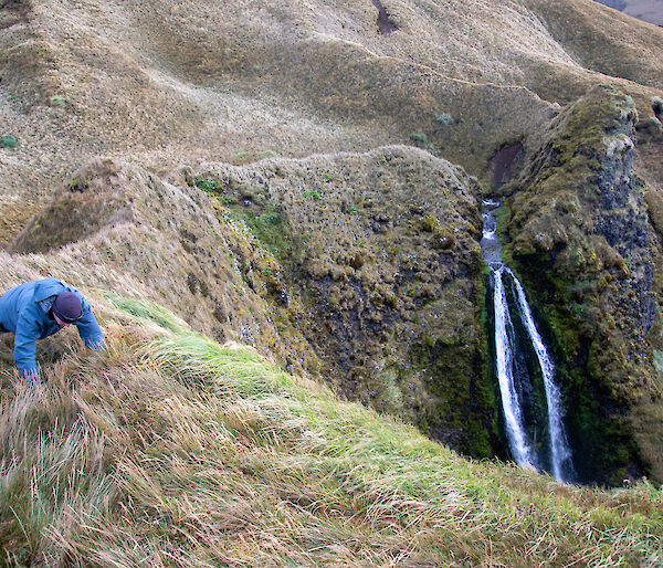 An expeditioner doing push ups on a ridge near a waterfall