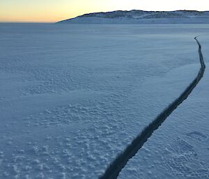 A curved tide crack in the sea ice between the peninsula and a nearby island