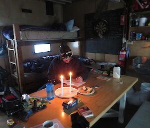 An expeditioner writing by candlelight in a field hut