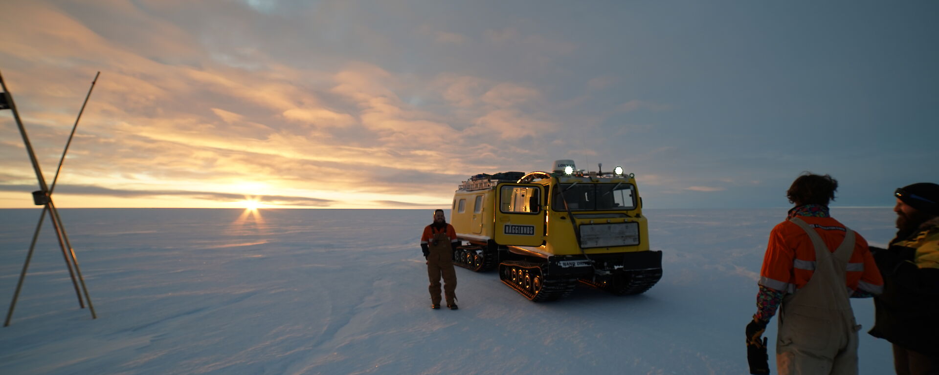 A group of expeditioners get ready to board a snow tracked vehicle on the ice