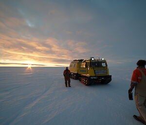 A group of expeditioners get ready to board a snow tracked vehicle on the ice